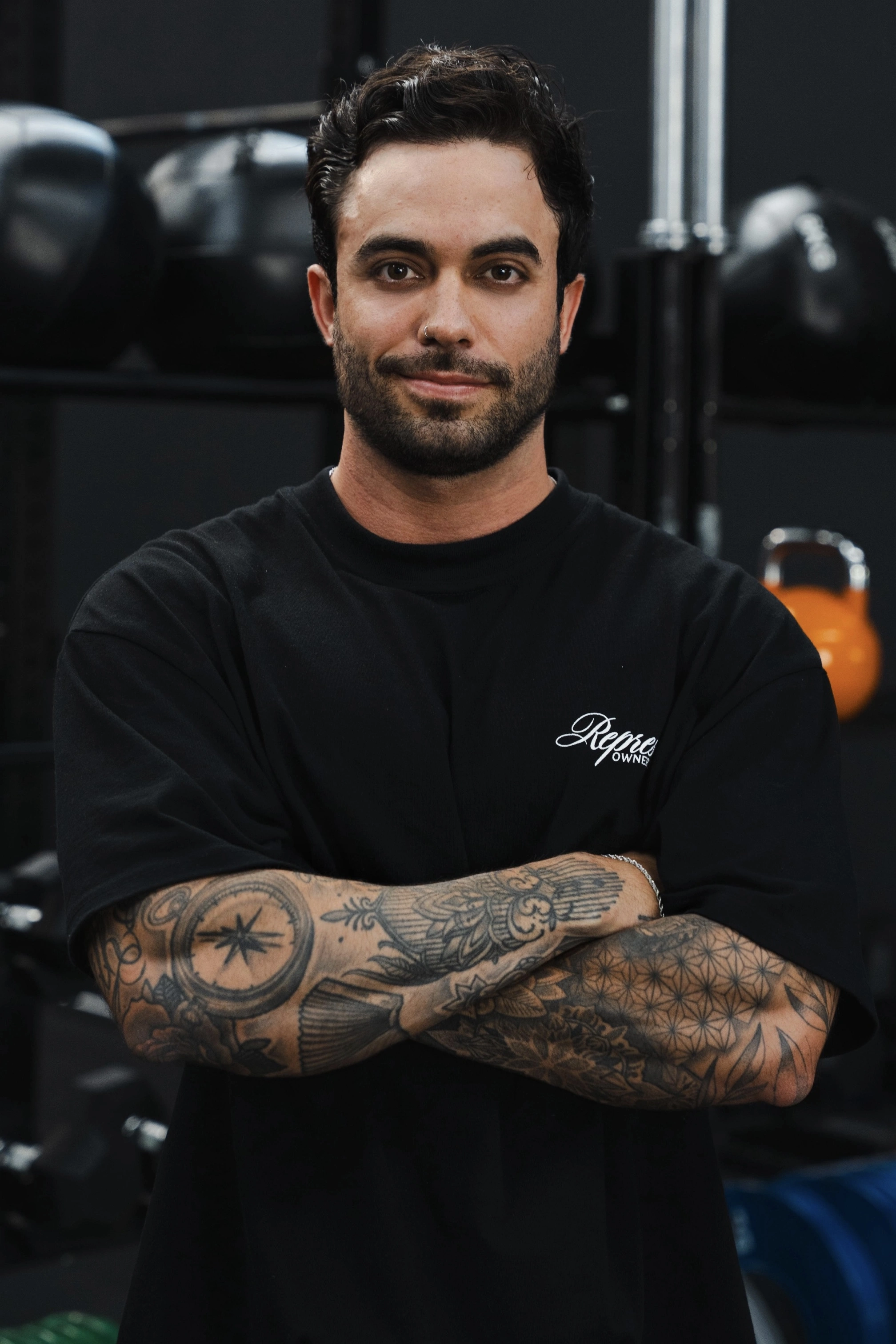 Close-up intenso de atleta profissional a executar deadlift pesado num ginásio industrial escuro com iluminação lateral dramática em laranja.